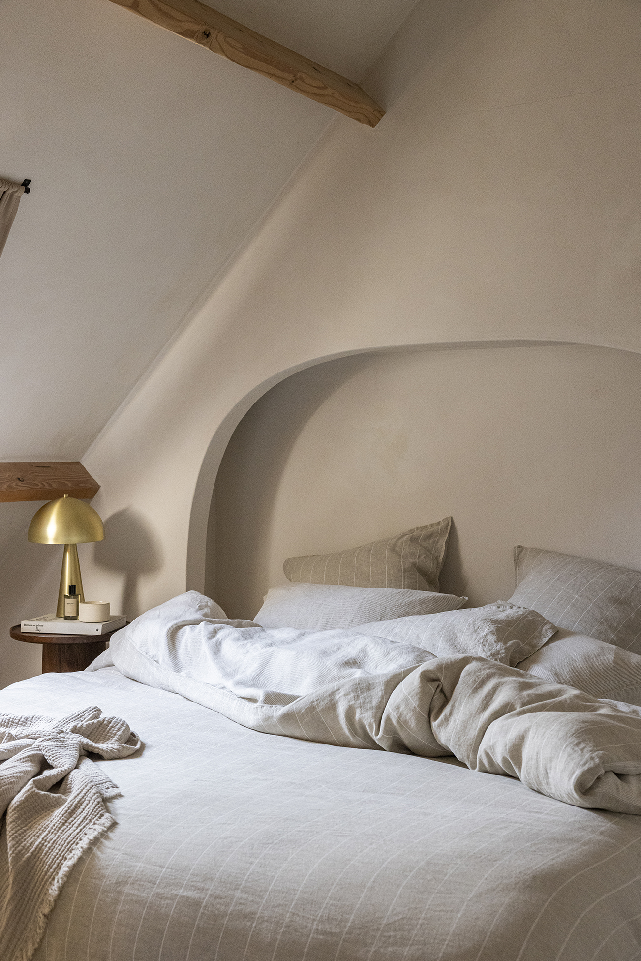 Un lit avec une parure en chanvre couleur naturel dans une chambre de couleur beige