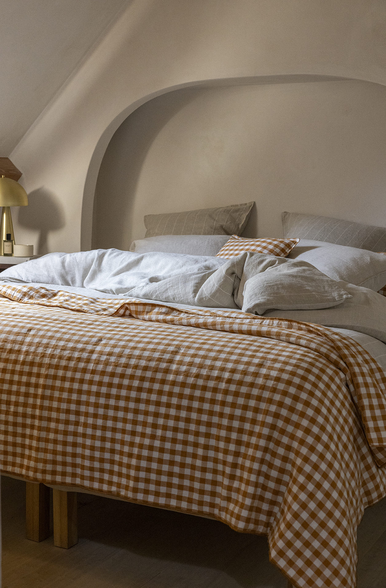Un lit avec une parure en chanvre couleur naturel et terracotta dans une chambre de couleur beige