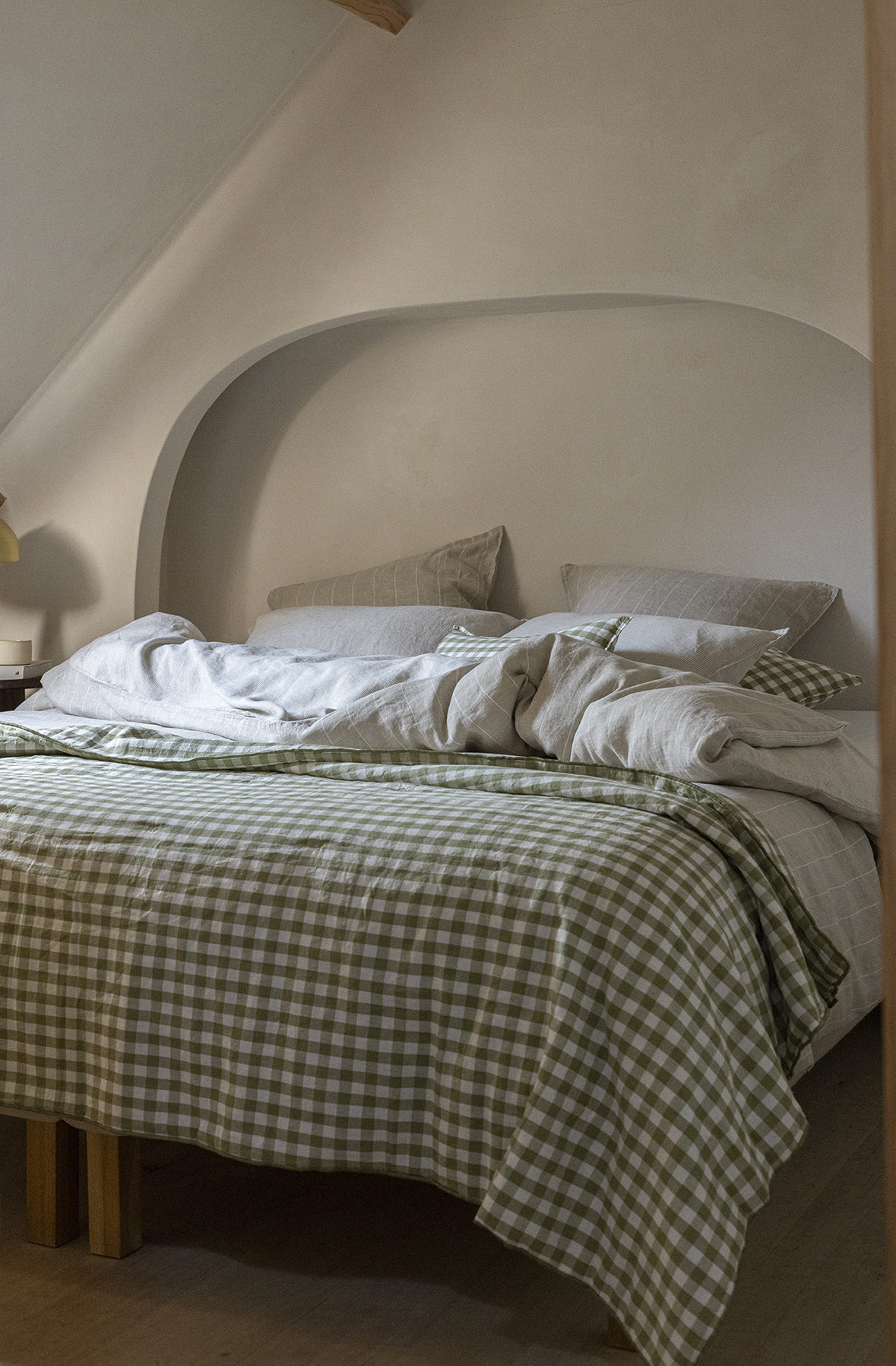 Un lit avec une parure en chanvre couleur vert dans une chambre de couleur beige