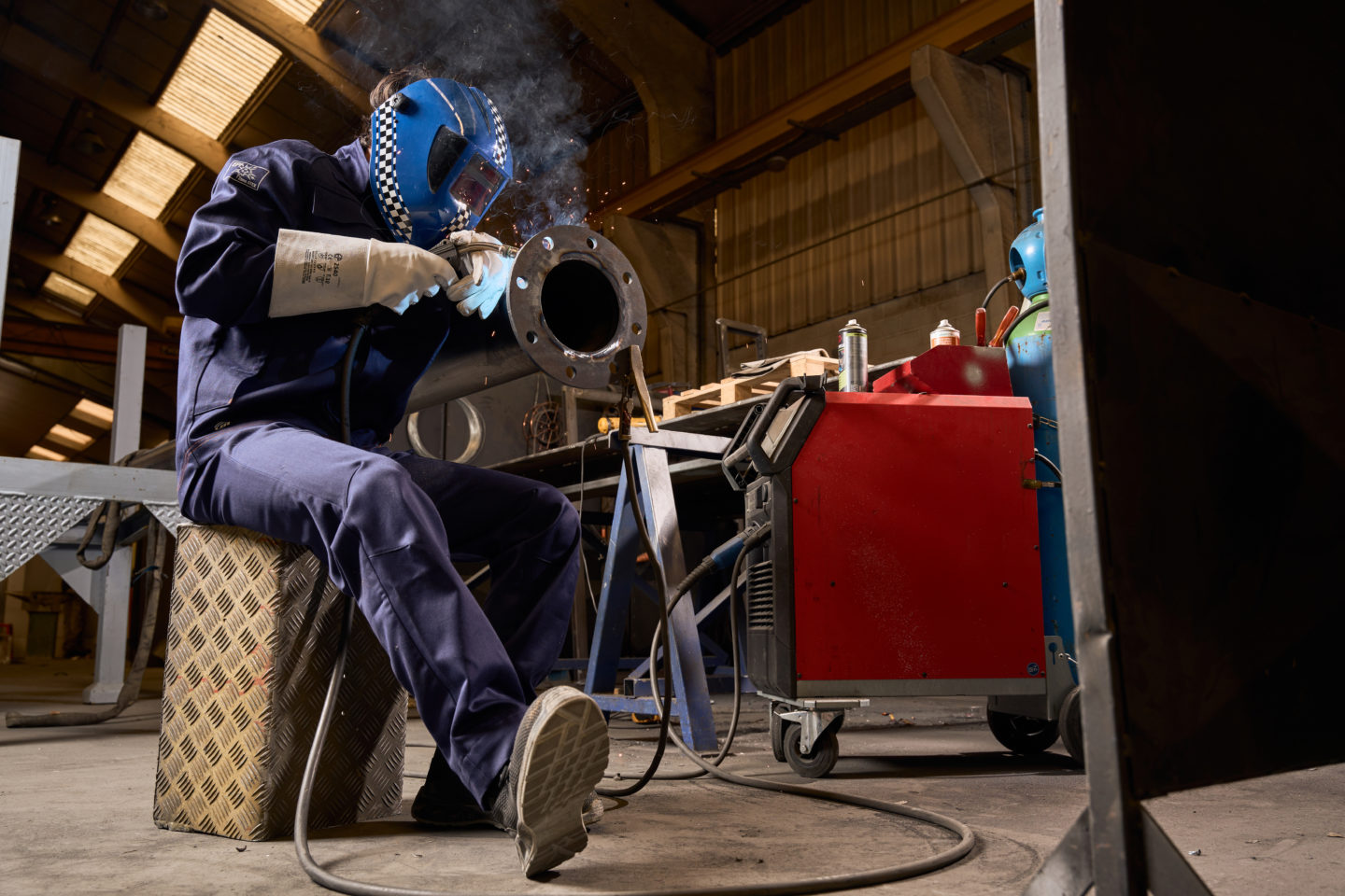 Homme en plein travail de soudure dans une chaudronnerie en tenue Invict Light bleue