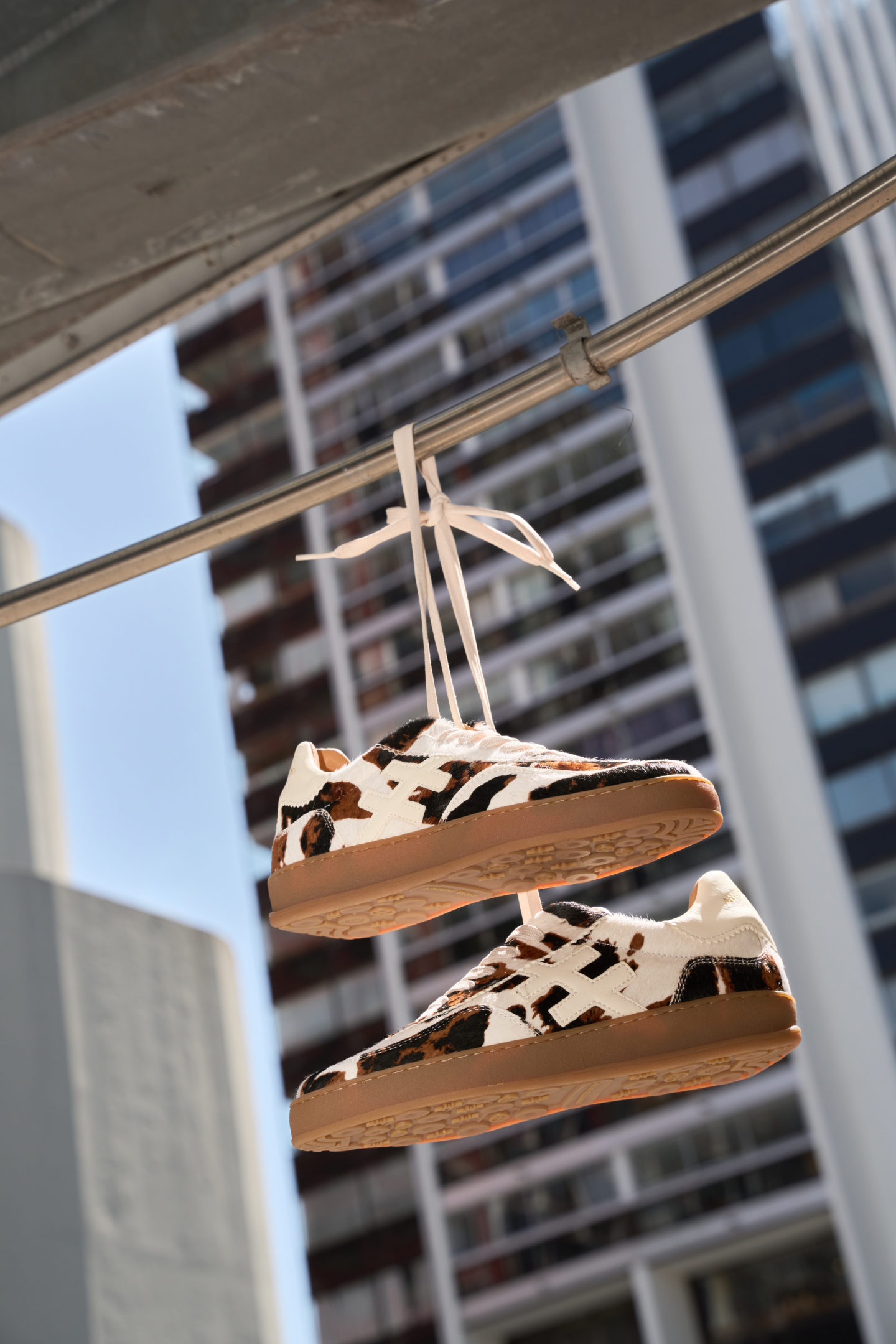 Paire de sneackers à motifs peau de vache accrochée à une rampe dans la rue