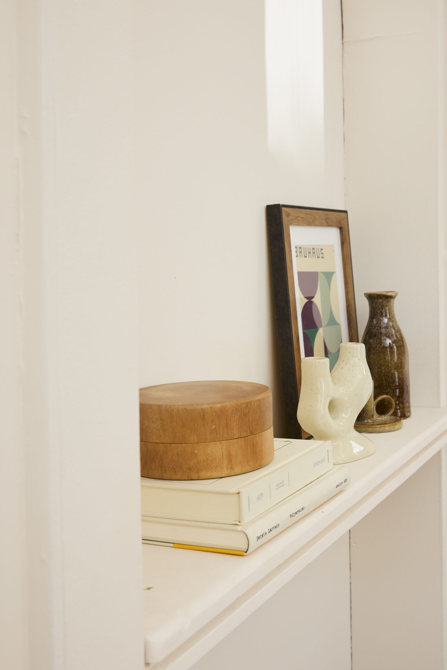 Etagère blanche avec livres, cadre et vases épurés dans les teintes brunes et blanches