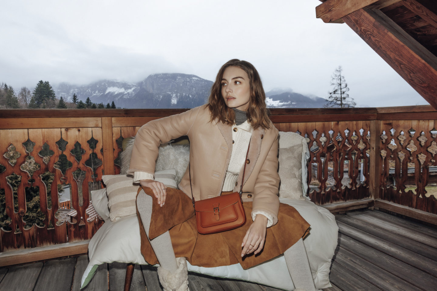 Femme assise sur le balcon d'un chalet avec un sac hexagona